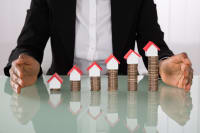 Businesswoman Protecting House Models On Stacked Coins